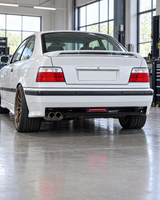 White BMW E36 coupe with lowered stance and bronze wheels, gloss black LED rear diffuser in a bright workshop; generated installation illustration
